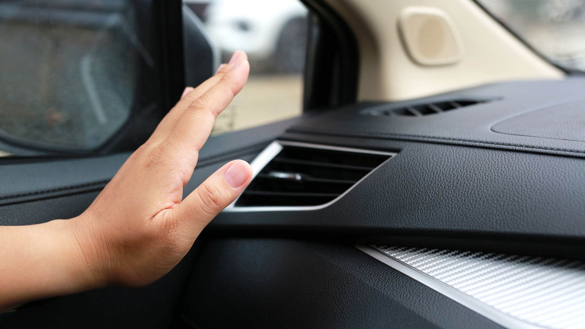a hand on the dashboard of a car.|a close up of a car dashboard with a digital interface.|a man working on a car with a wrench.