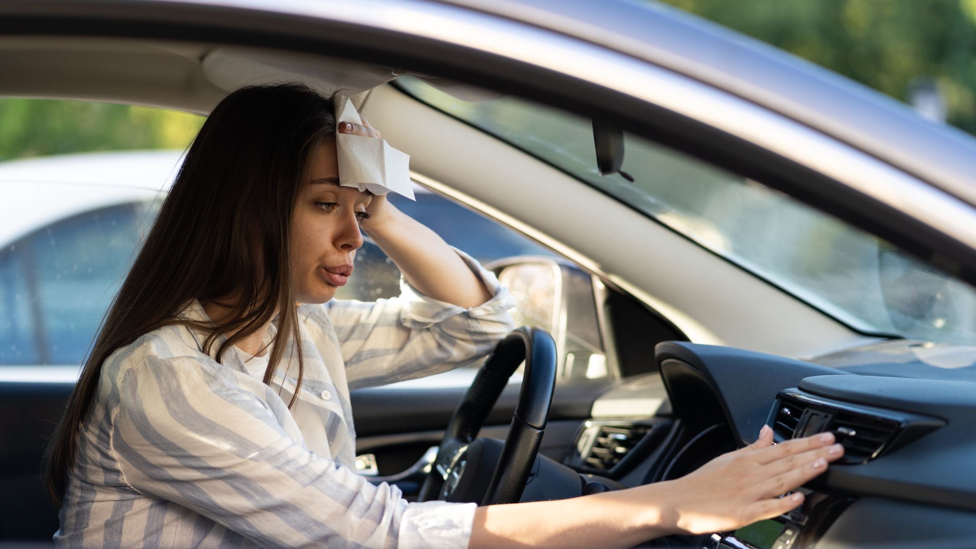a woman sitting in a car with her hand on the steering wheel.|a hand on the dashboard of a car.|a man holding a blue and black object in his hands.