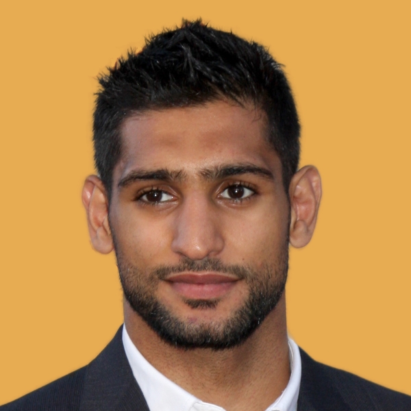 A man in a suit and tie is standing in front of a yellow background.