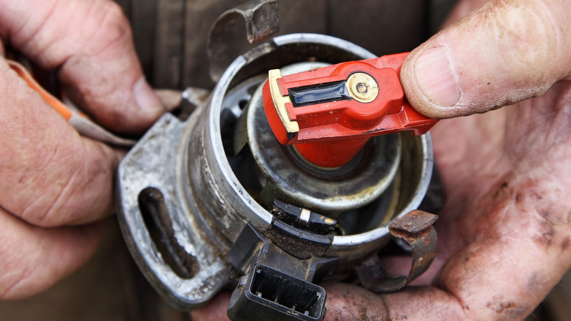 a close up of a person holding a wrench.|a close up of a carburet on a white background.|a person holding a wrench in front of a car engine.
