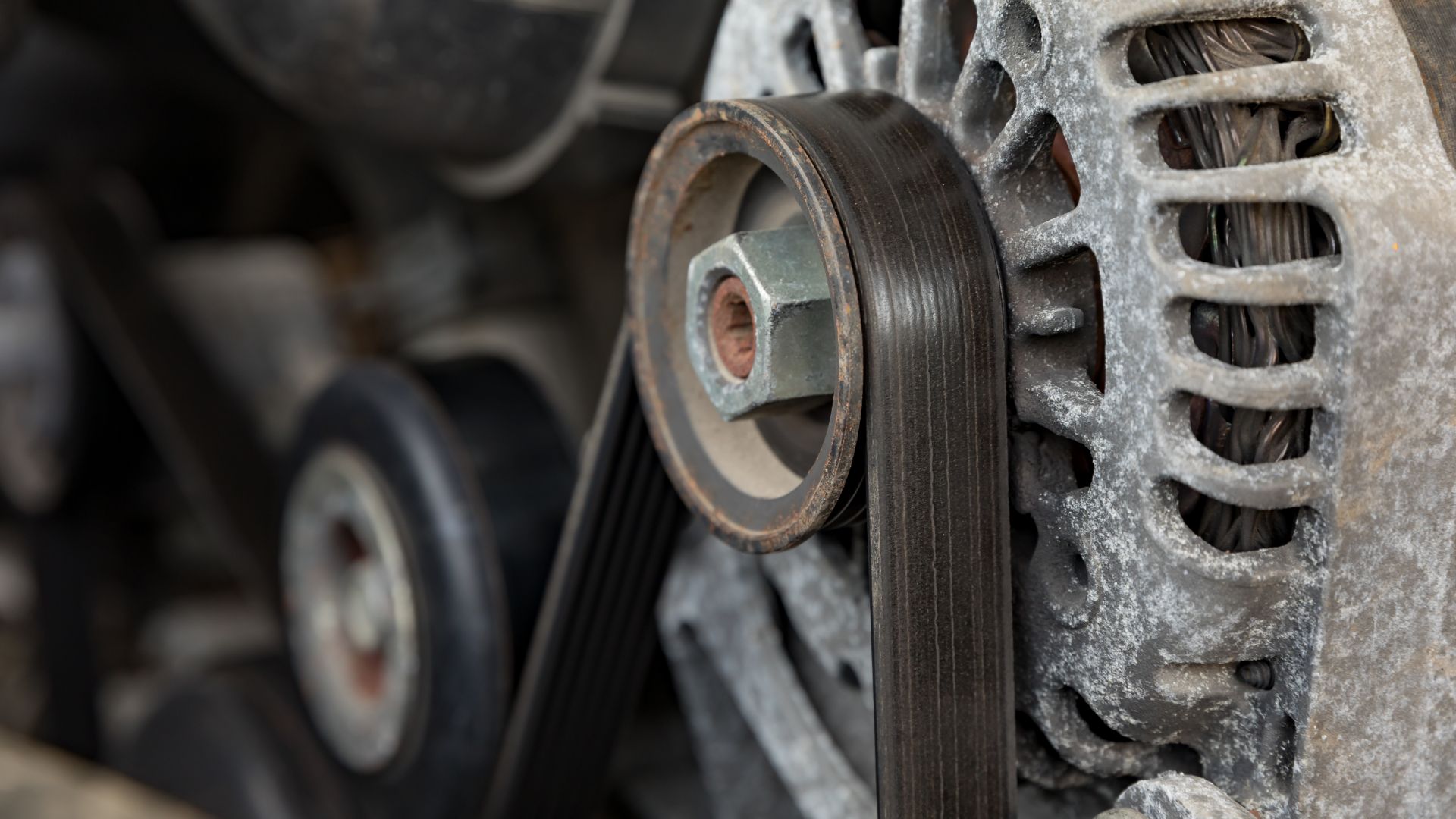 a close up of a metal gear on a vehicle.|a close up of the engine of a car.|a man is working on a car engine.