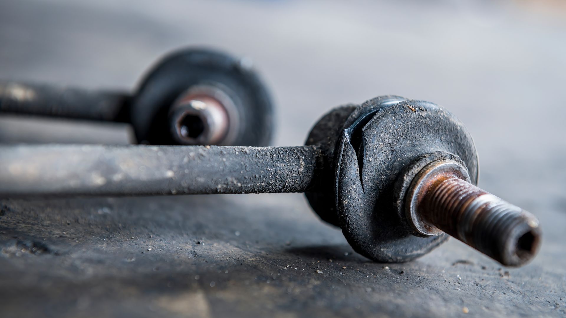 a close up of a metal object on the ground.|a couple of screws sitting on top of a metal table.|a pair of metal bars with a white background.|a close up of a car's brake assembly.