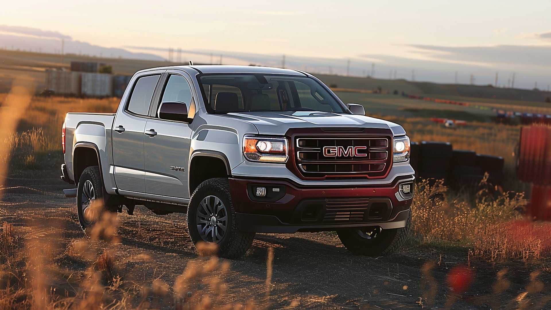 The 2019 GMC Canyon is driving down a dirt road.|a red truck driving down a road near mountains.
