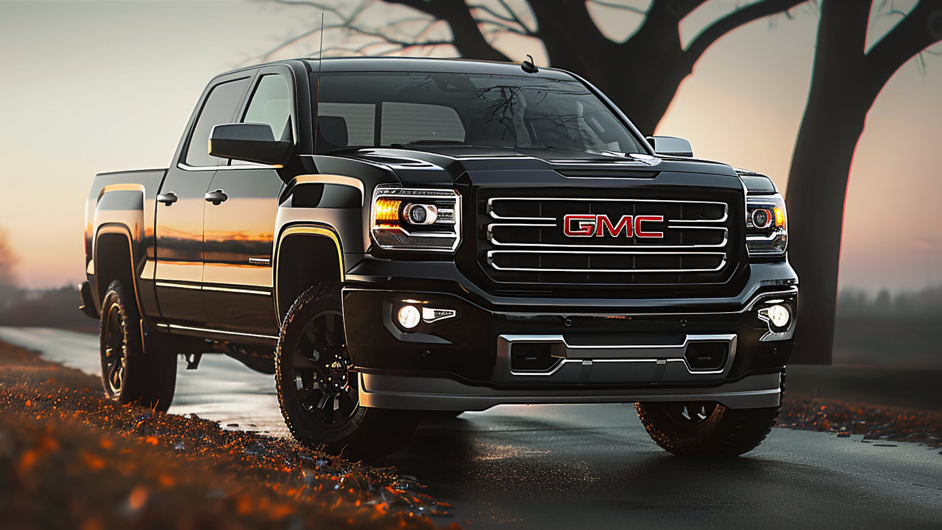 A black GMC Sierra truck, from one of the years to avoid, is driving down a road.|a black truck is shown in a studio.