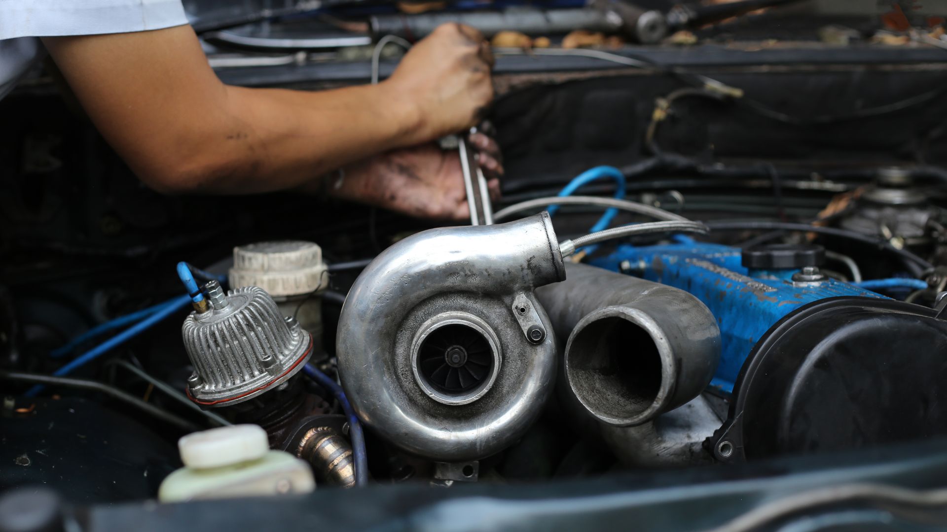 a close up of a person working on a car engine.|a car with a lot of smoke coming out of it.|a close up of a person holding a metal object.