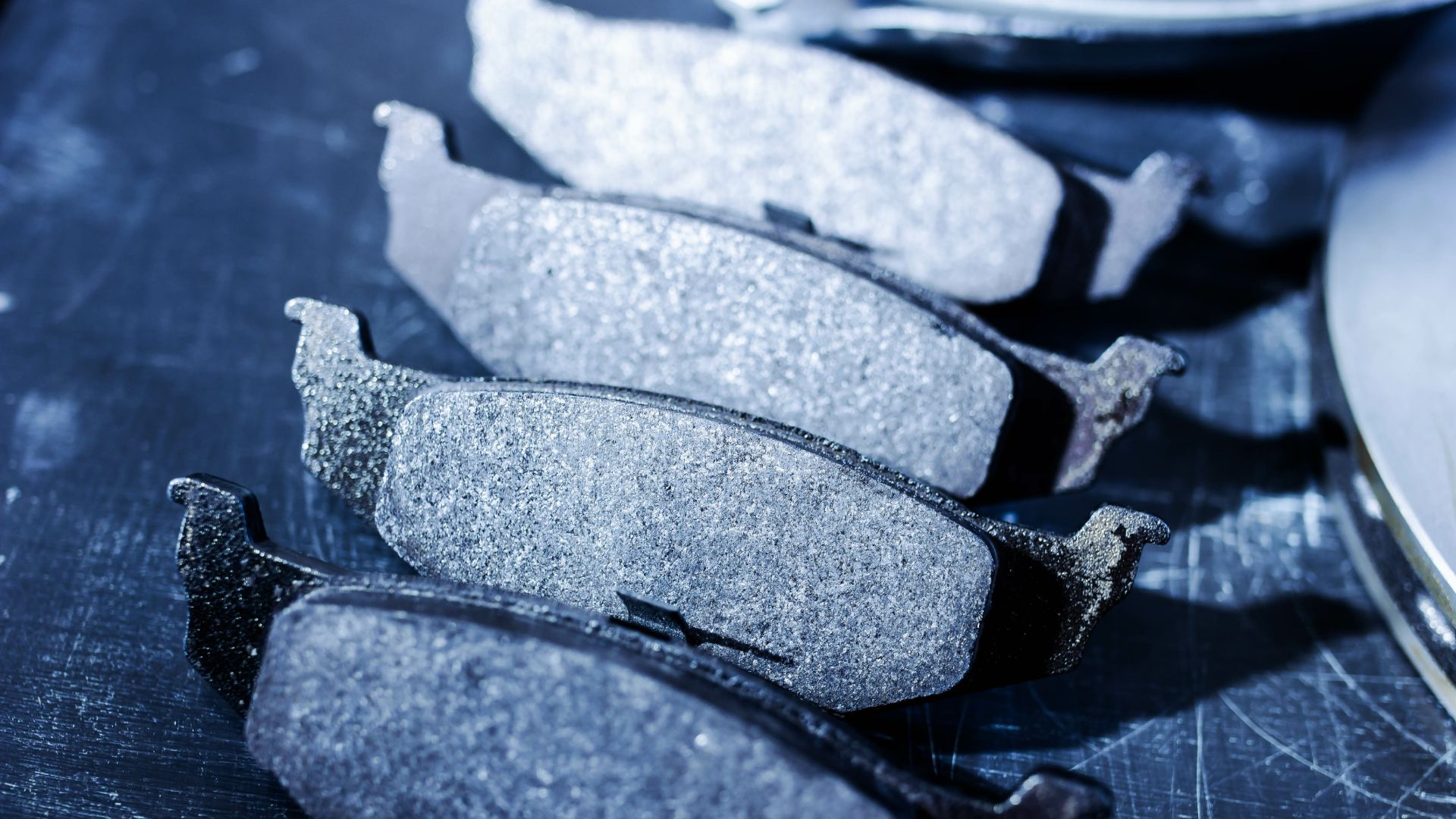 a box of brake pads and tools on a table.|a couple of wrenches sitting on top of a table.|a person holding a pair of gloves and a piece of wood.