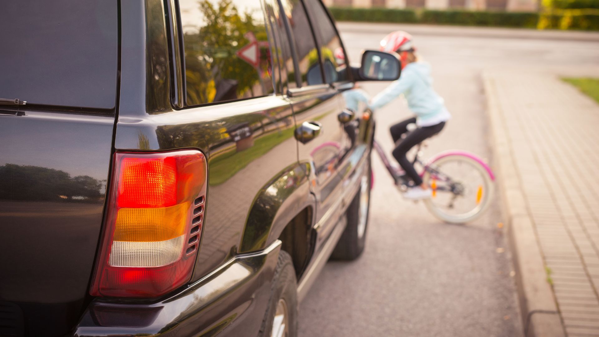 a man riding a bike next to a parked car.