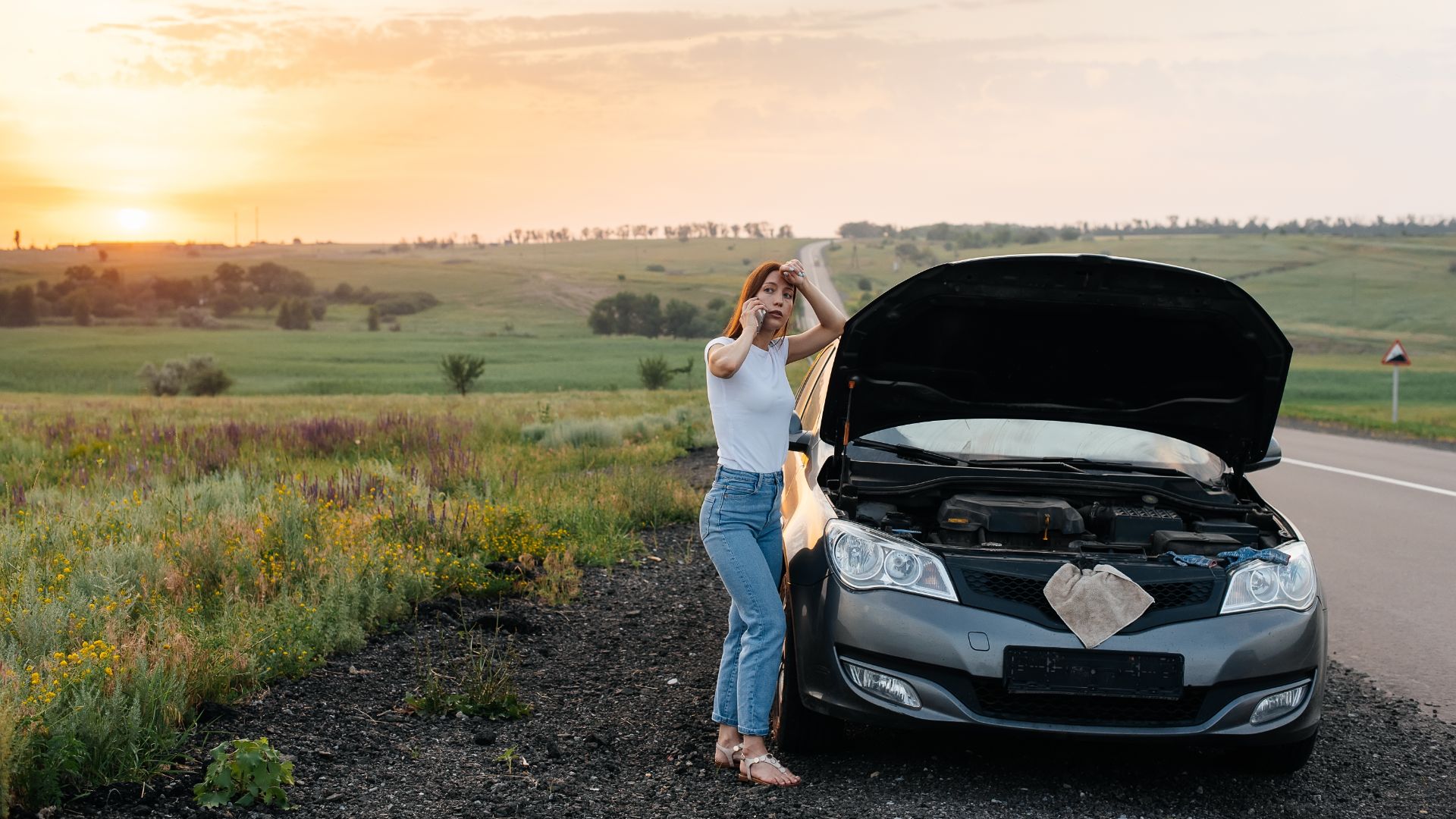 a woman standing next to a car on the side of the road.