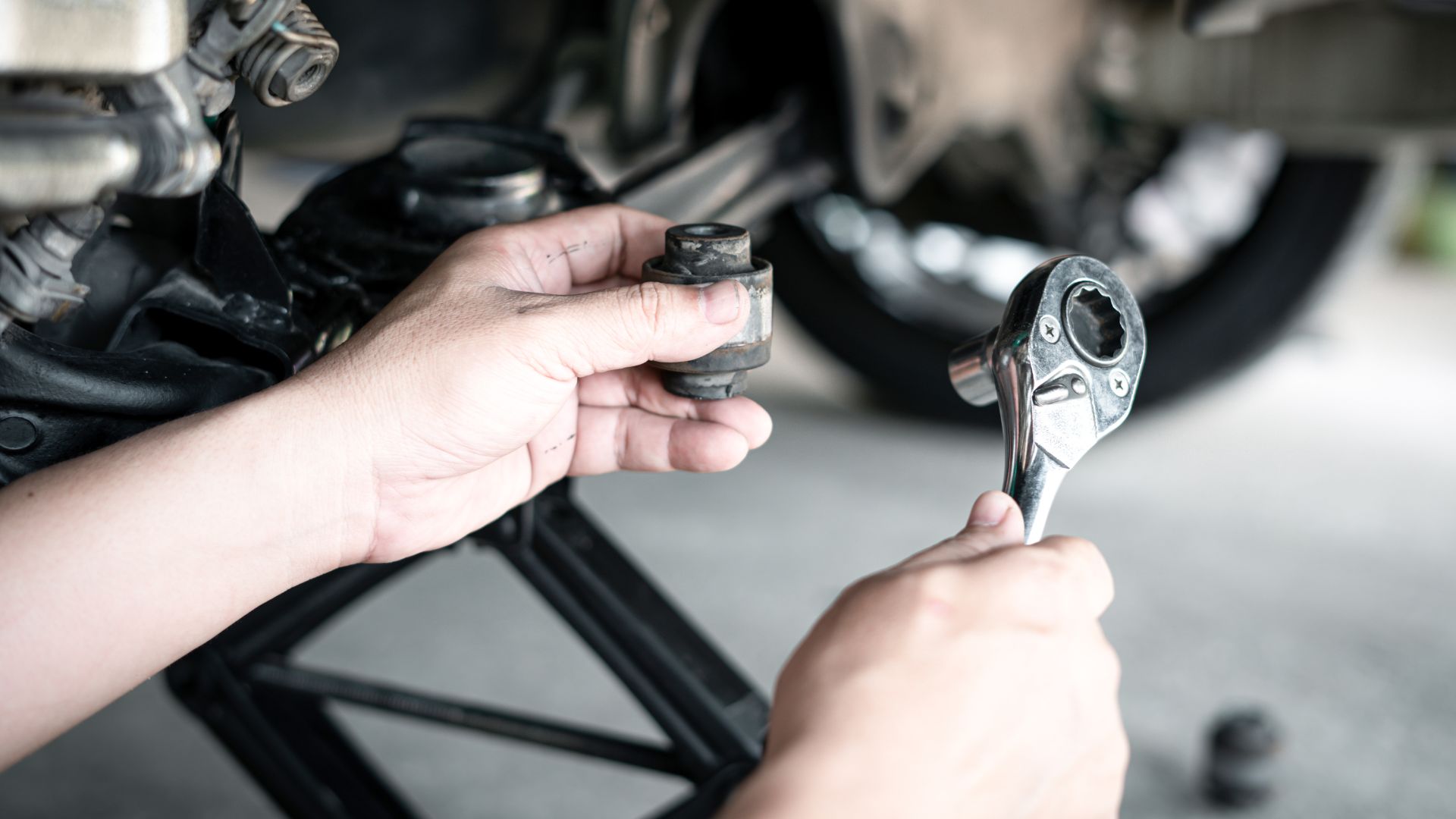 a close up of a person holding a wrench.|a man working on a vehicle with a wrench.
