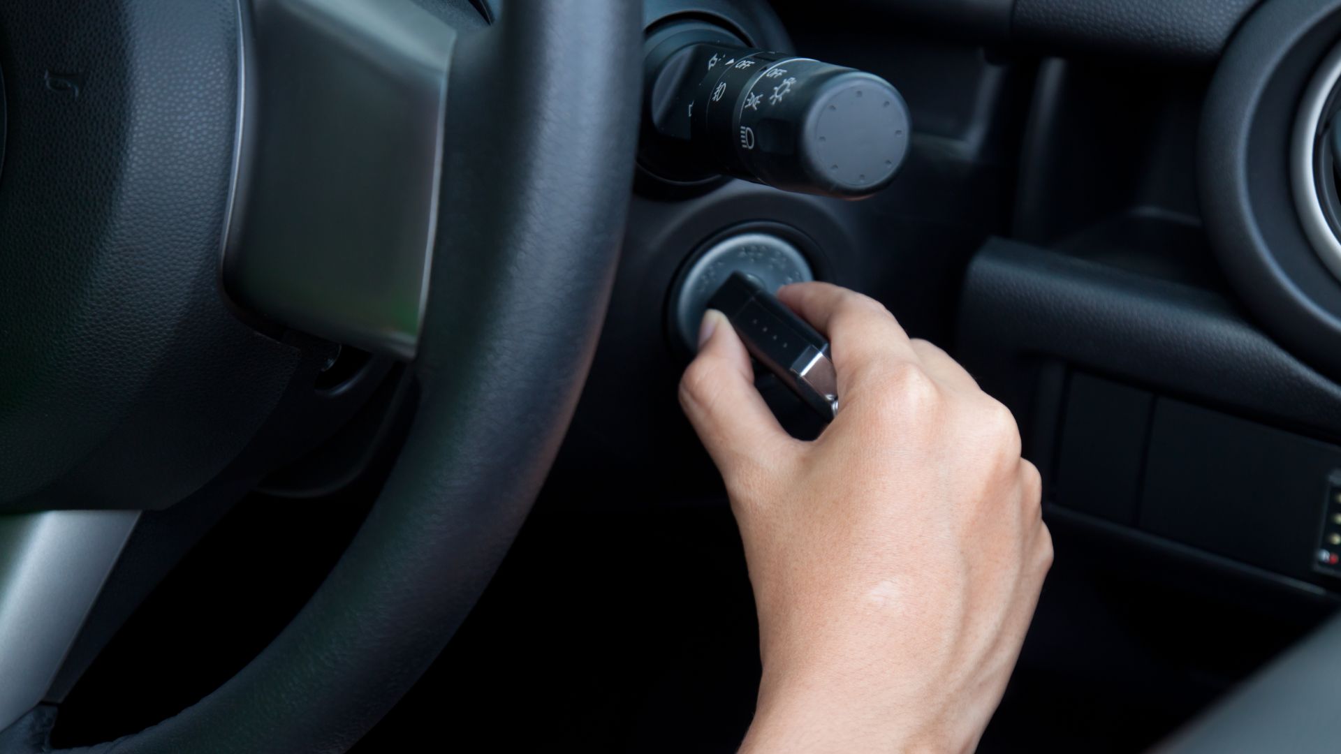 a person holding a cell phone while driving a car.|a man is working on a car engine.