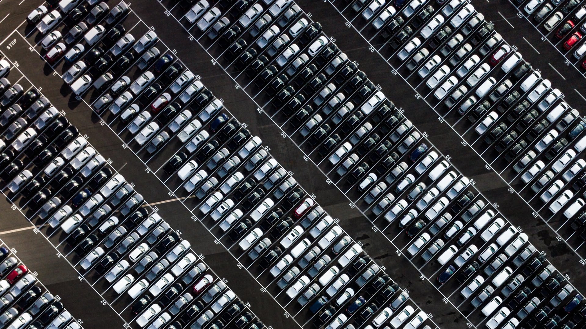a parking lot filled with lots of parked cars.|an assembly line with a car being worked on.|an assembly line with cars on the assembly line.