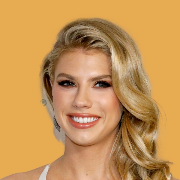 A blond woman smiling on an orange background.