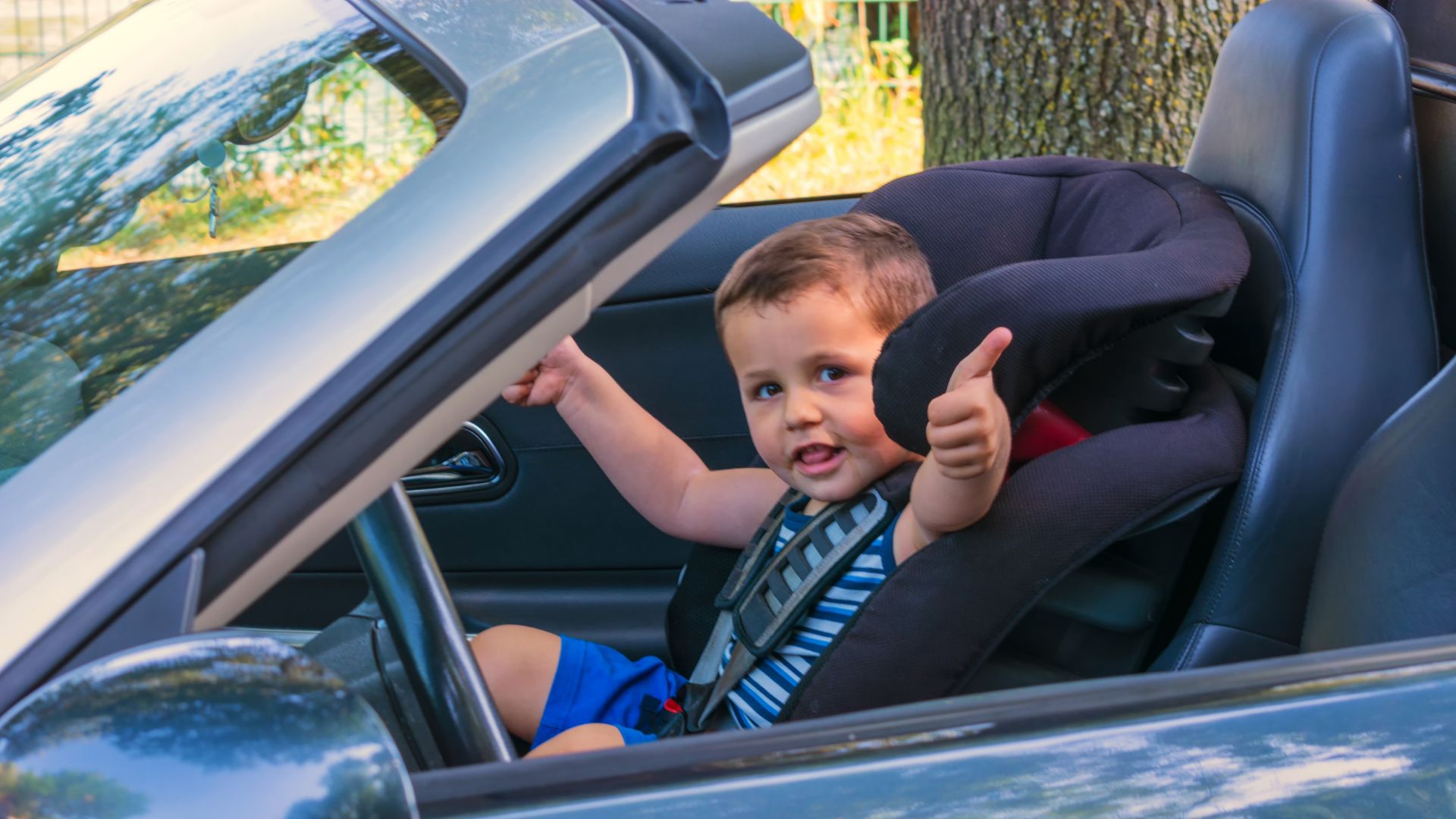 a little boy sitting in a car seat giving a thumbs up.|a woman feeding a baby in a car seat.|a woman holding a baby in a car seat.