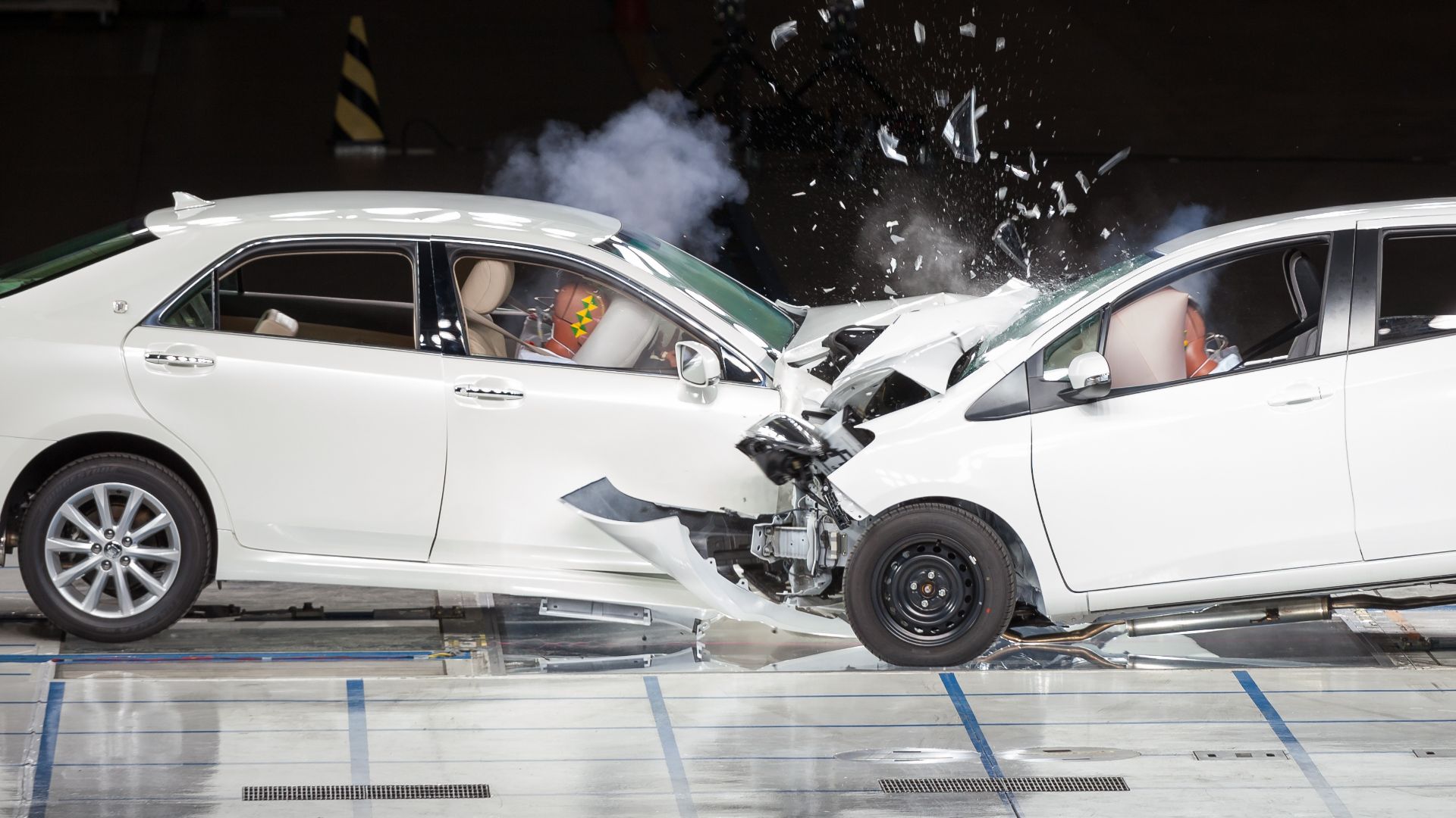 a couple of cars that are in a garage.|a close up of a white car with black paint on it.