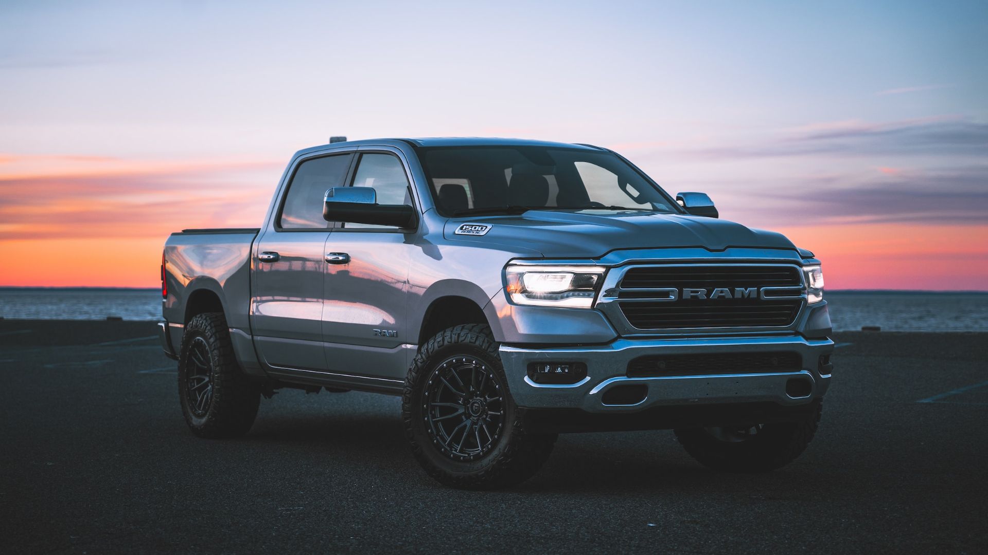 a silver ram truck parked in front of a sunset.|the interior of a truck with the door open.