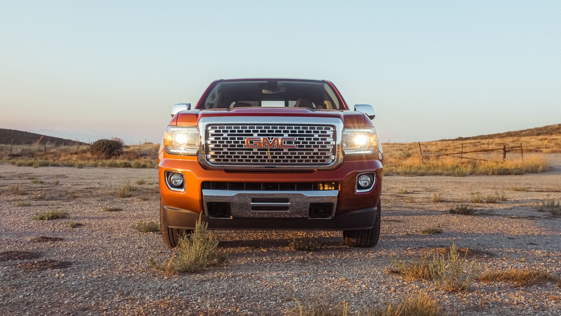 a red truck parked in the middle of a desert.|a black truck parked in front of a house.