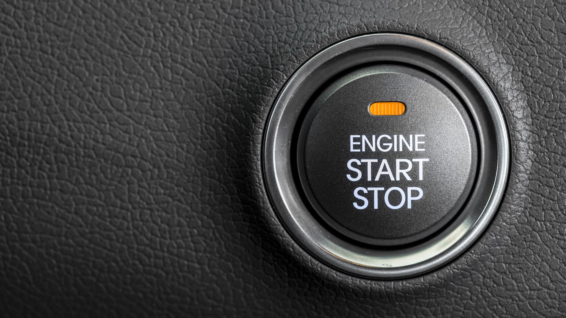 an engine start button on a car.|a person holding a wrench in front of a car engine.