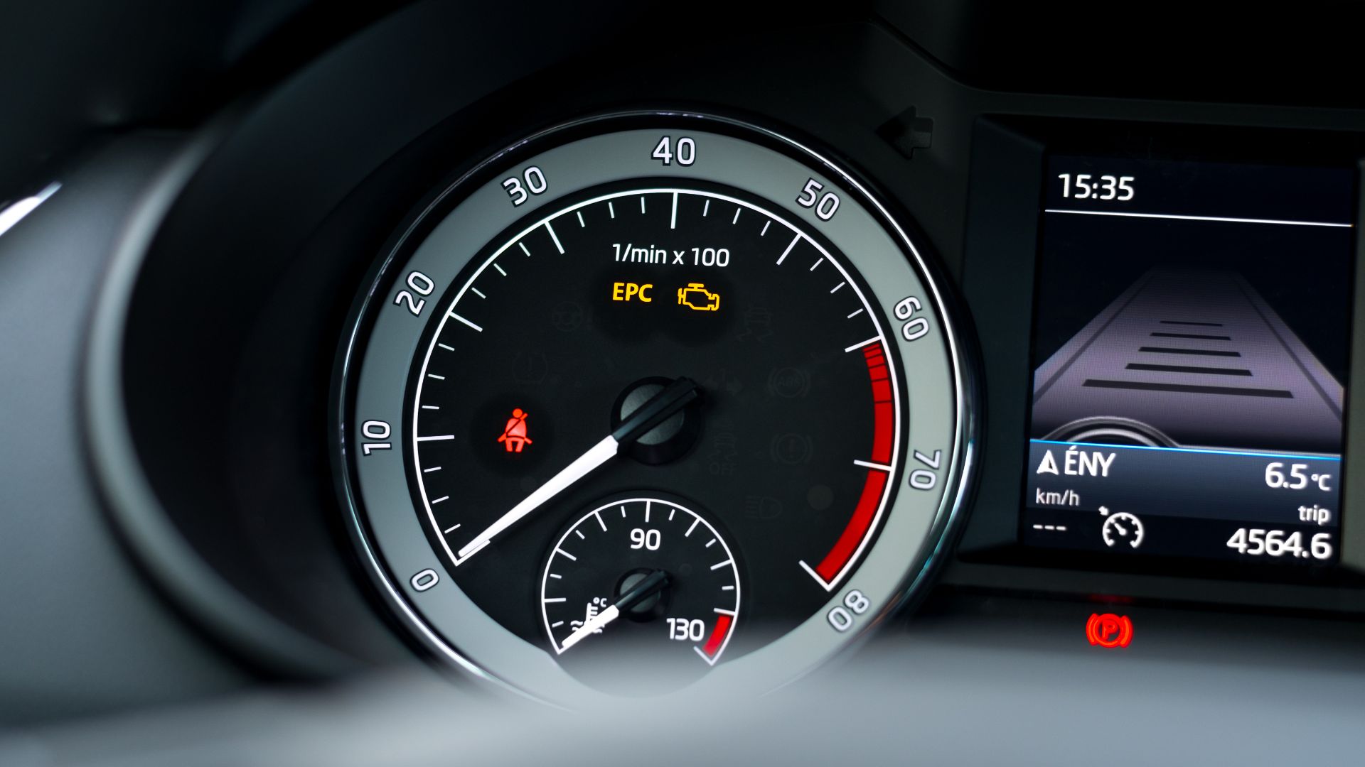 a close up of a speedometer in a vehicle.|a black car parked in a parking lot.|a man wearing gloves and holding a wrench.