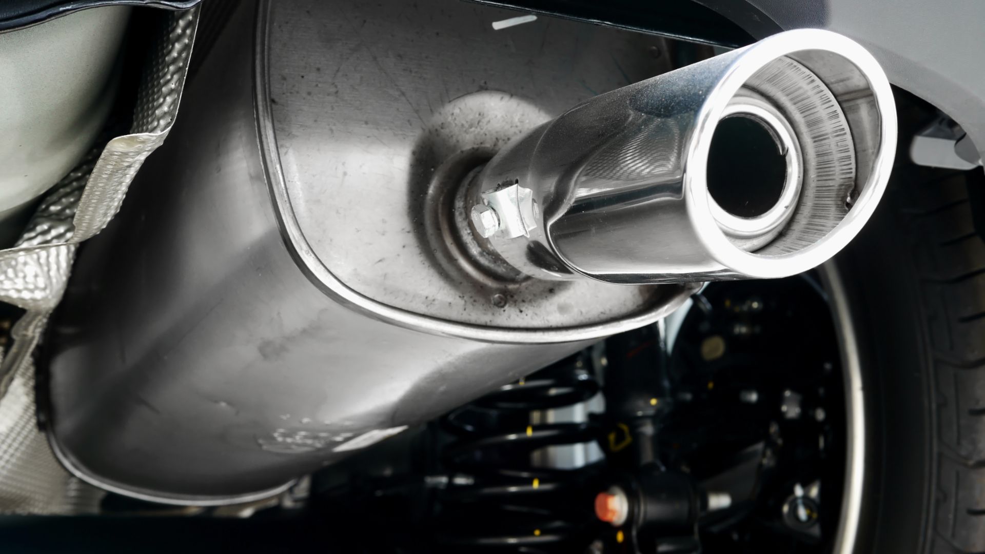 a close up of a car's exhaust pipe.|a close up of a motorcycle exhaust system.