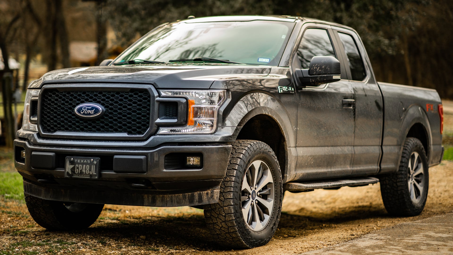 a silver truck parked on a dirt road.