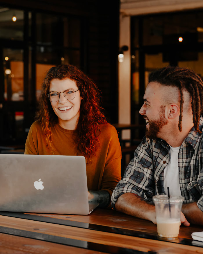 Two people sitting at a table with a laptop.