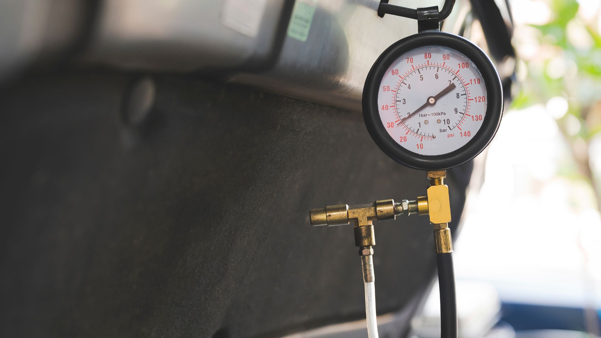 a pressure gauge attached to the side of a car.|a person pressing a button on a car's steering wheel.