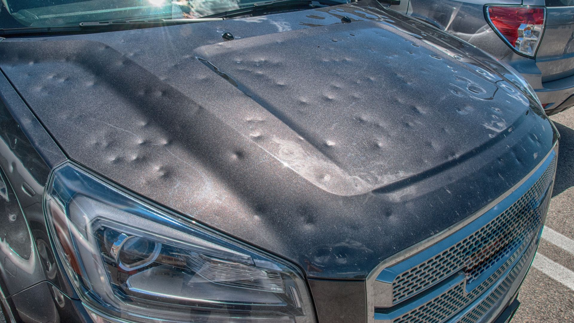 a close up of a car with a mattress on the hood.|a car covered in snow with a person sitting on top of it.