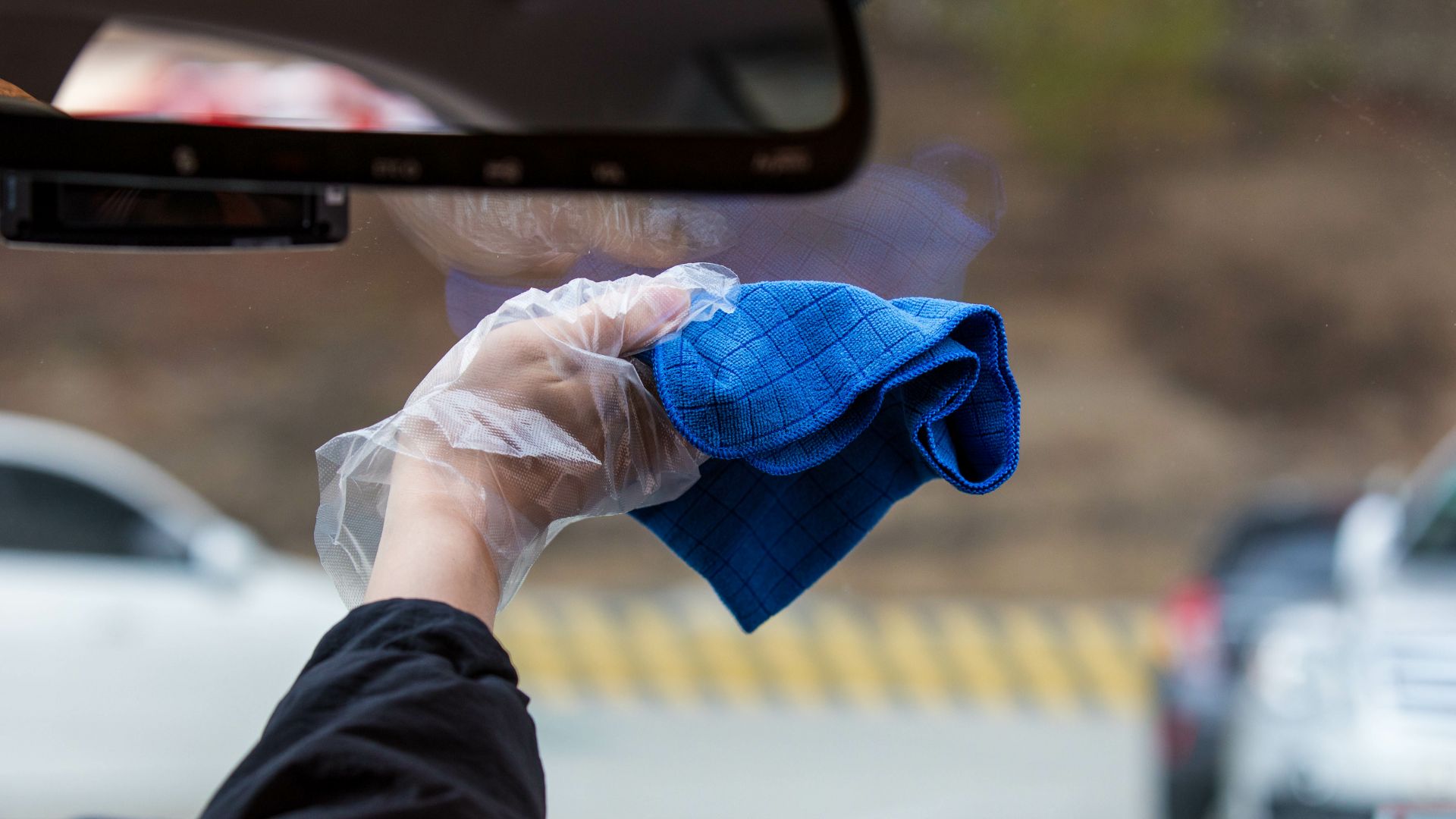 a person holding a blue cloth in their hand.|a woman sitting in the drivers seat of a car.