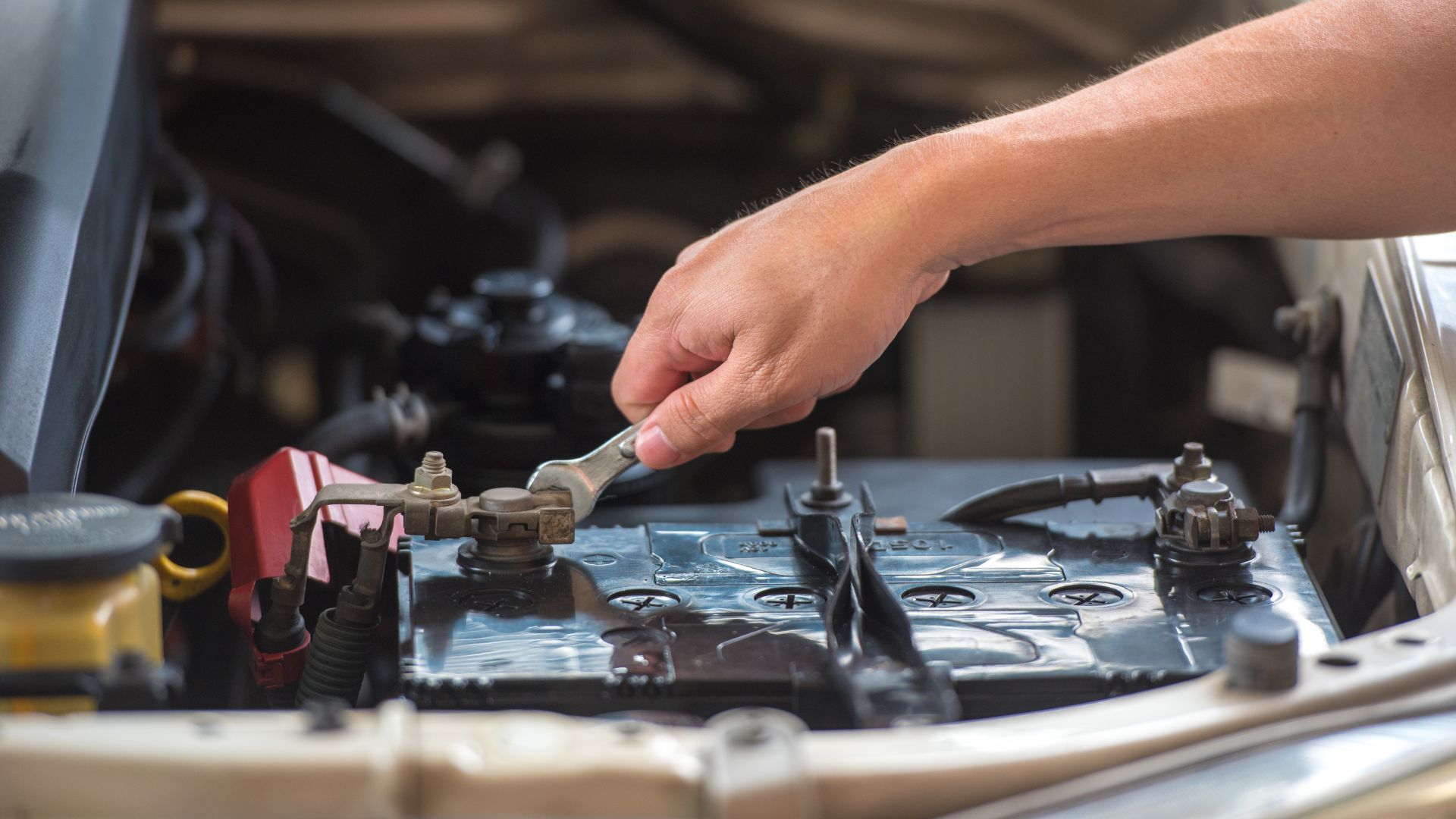 a man is working on a car's engine.|a man is working on a car battery.