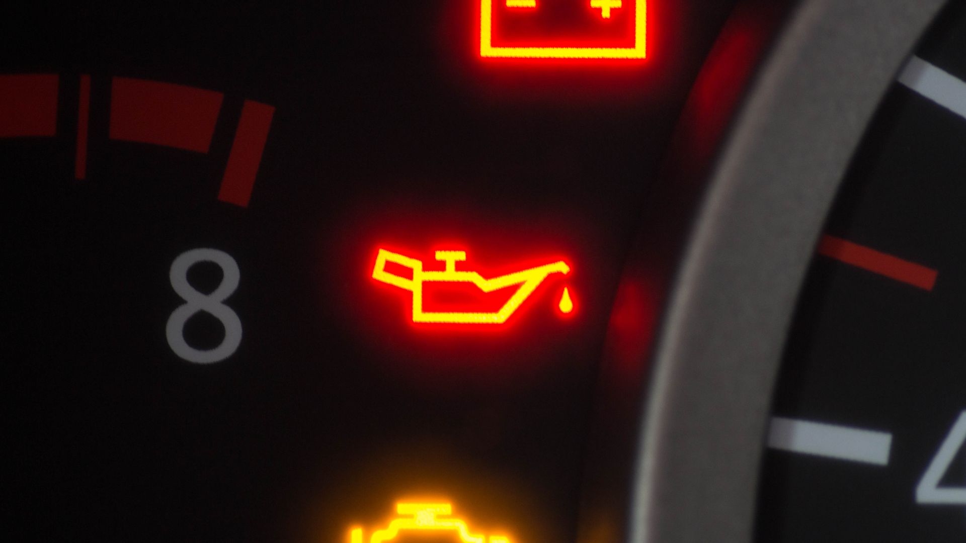 a close up of a speedometer with red and yellow lights.|a man is working on a car with a pressure gauge.