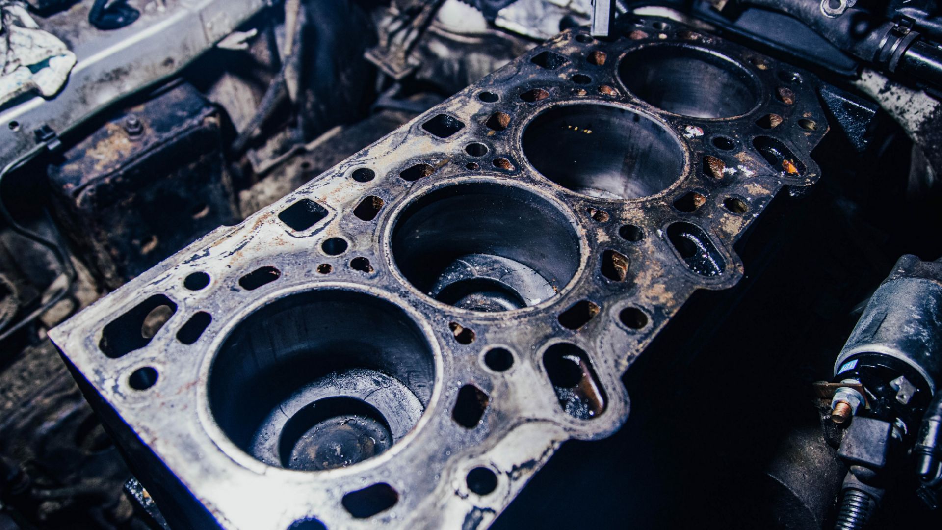 a close up of an old engine block.|a close up of an old engine block.|a man working on an engine in a garage.|a close up of an engine block on a car.|a close up of an engine block in a vehicle.