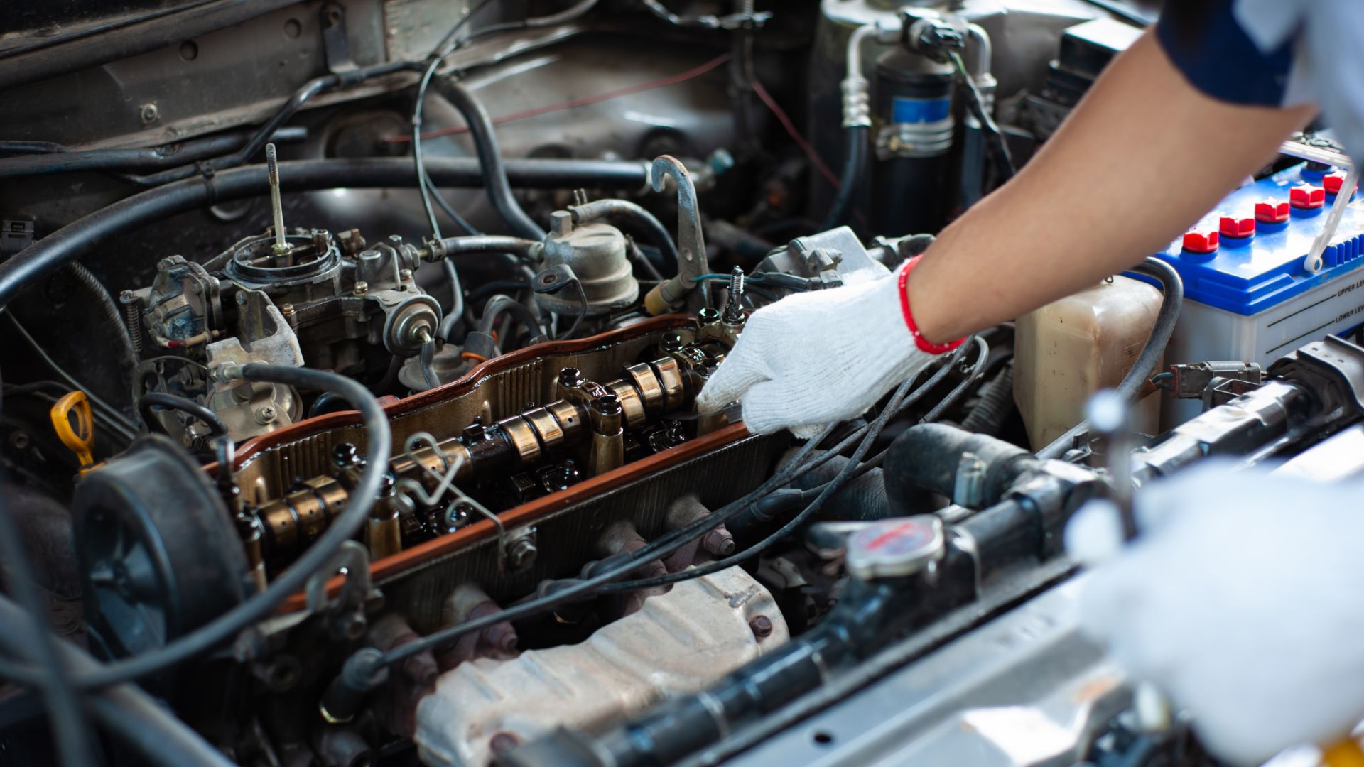 a person working on an engine in a car.|the engine compartment of a car is shown.|a man is working on a car engine.