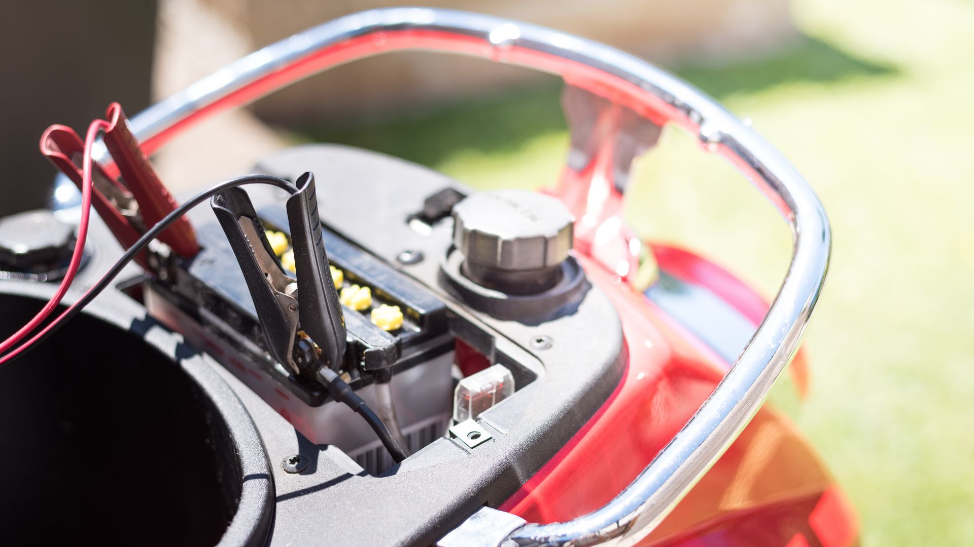 a close up of a motorcycle's battery box.|a man working on a motorcycle in a garage.