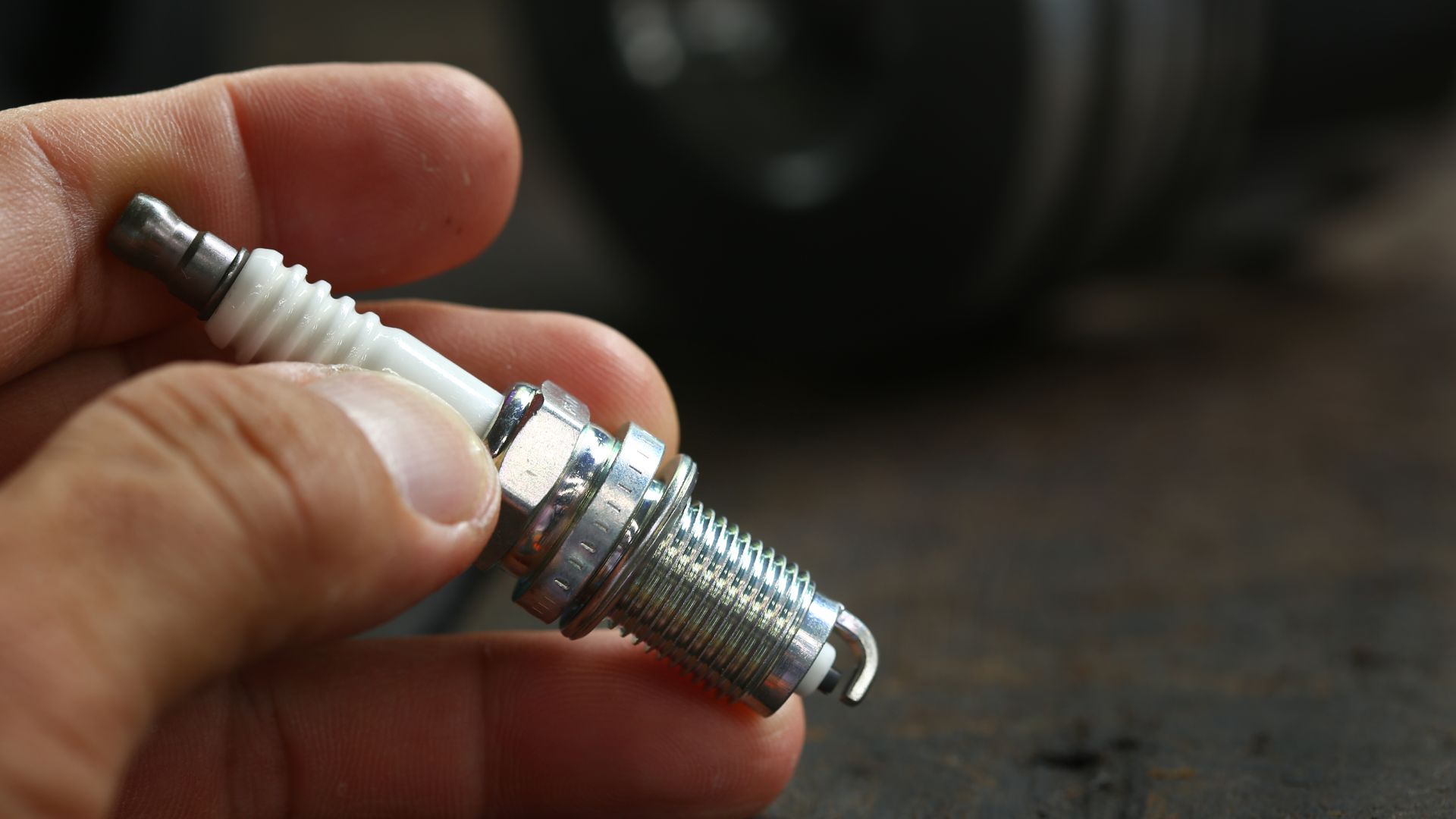 a person holding a small metal object in their hand.|a man holding two screws in his hand.