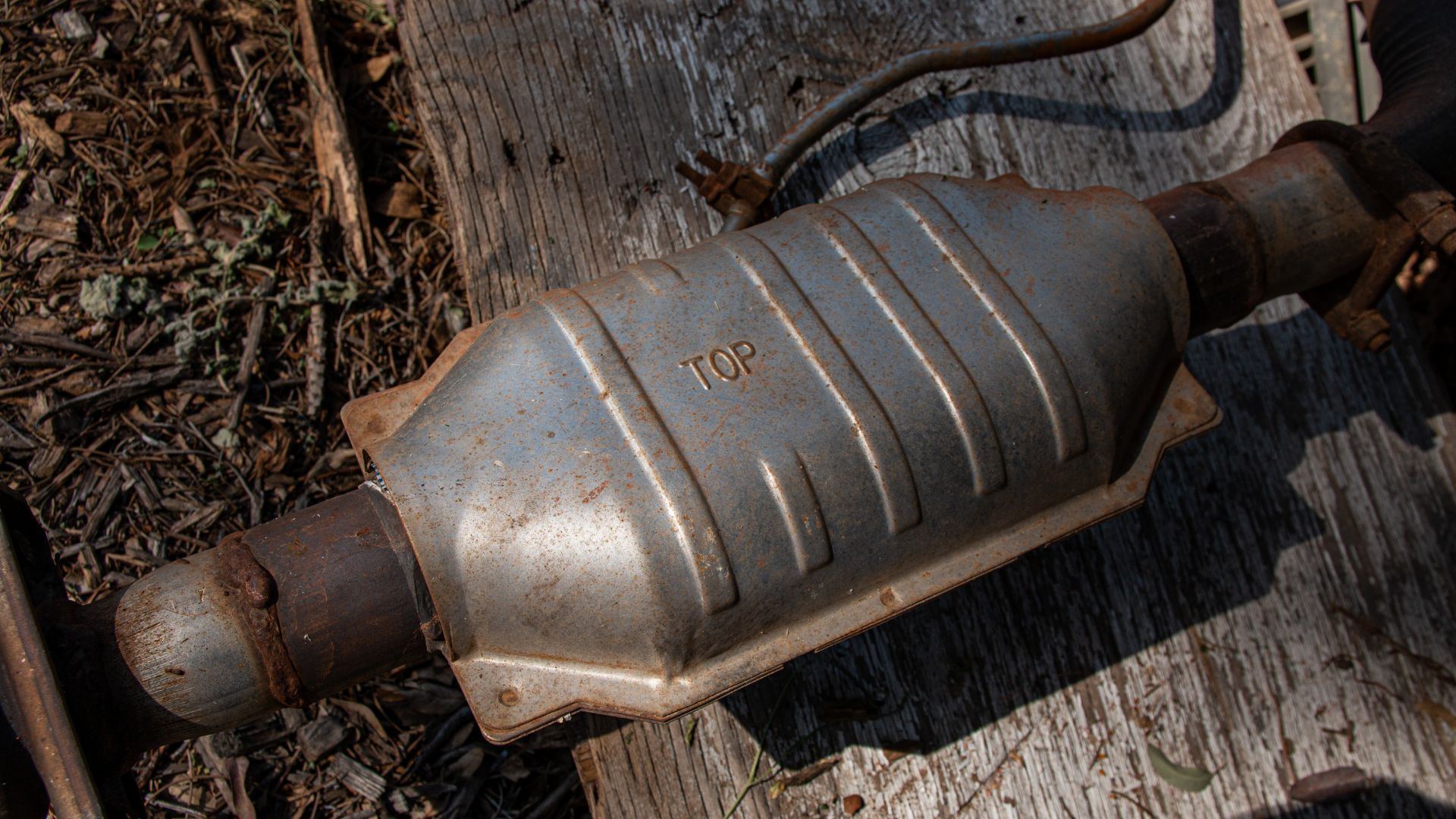 an old metal object sitting on top of a wooden table.|a pile of old metal pipes stacked on top of each other.