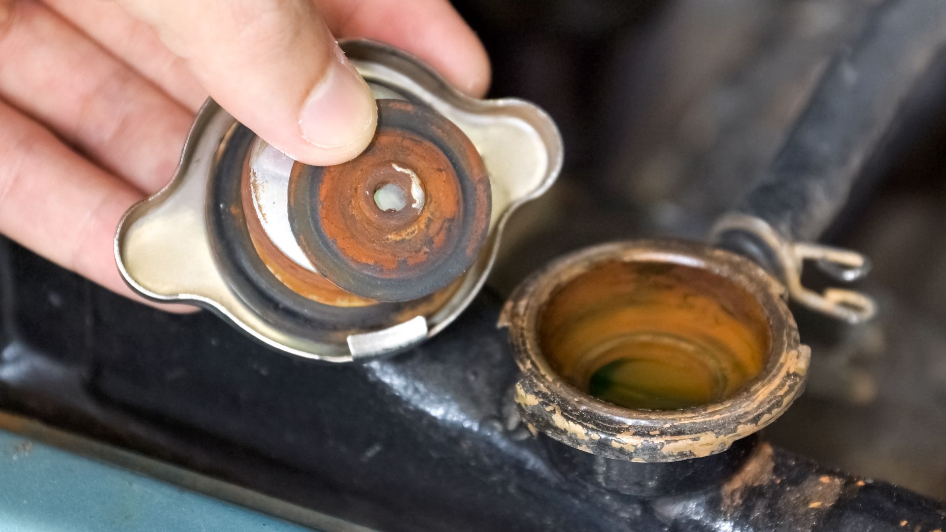 a person is holding a metal object in their hand.|a man is working on a car battery.