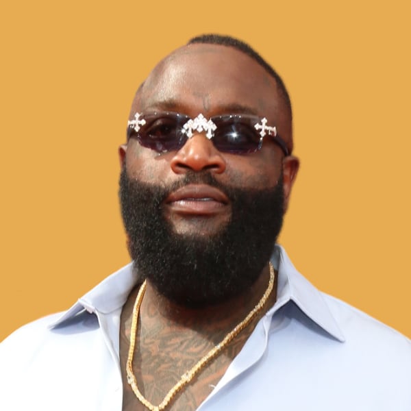 a man with a beard wearing sunglasses.|a white jeep driving down a dirt road next to the ocean.