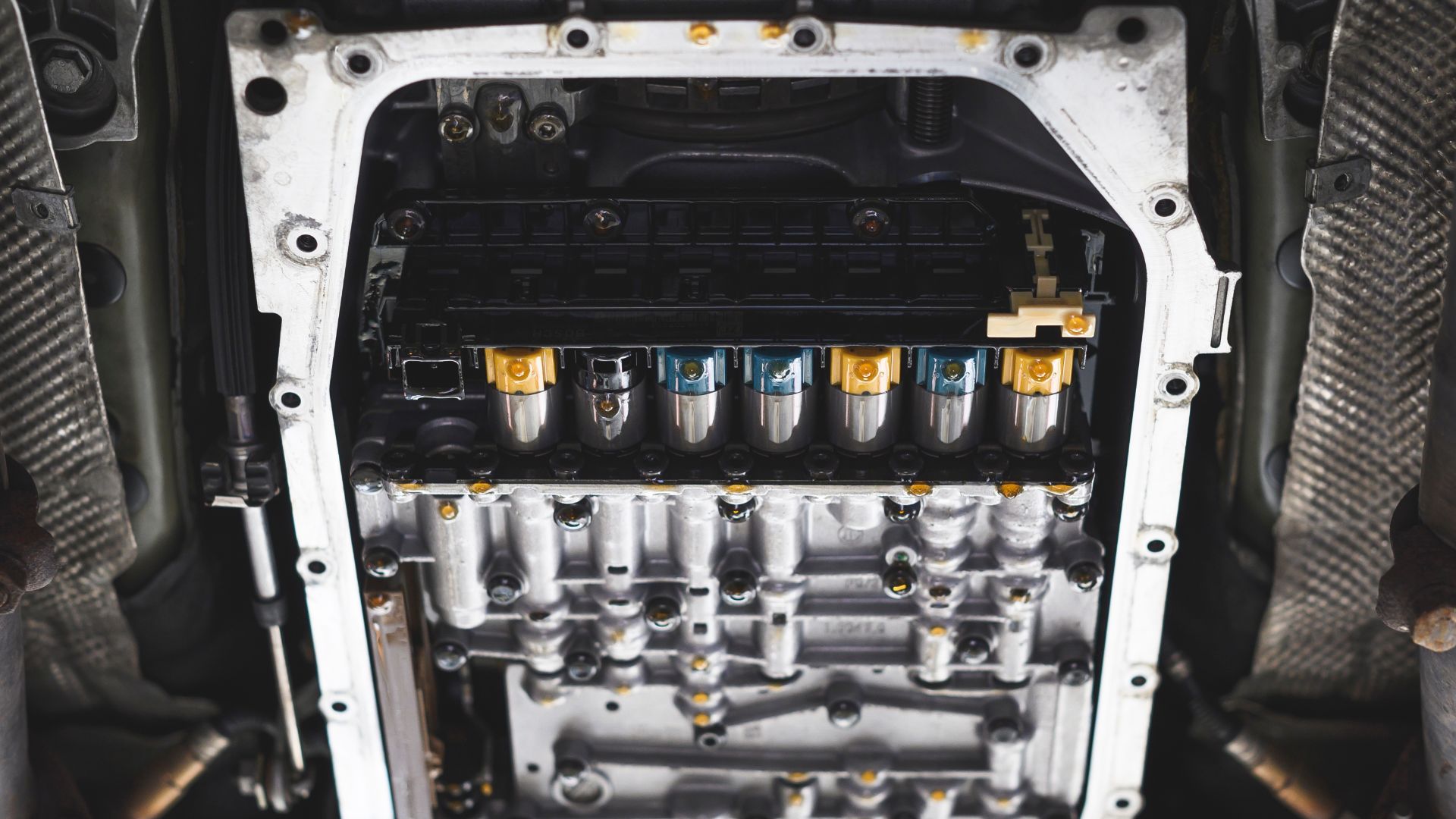 the engine compartment of a vehicle with the top part of the engine exposed.|a close up of a steering wheel knob on a car.