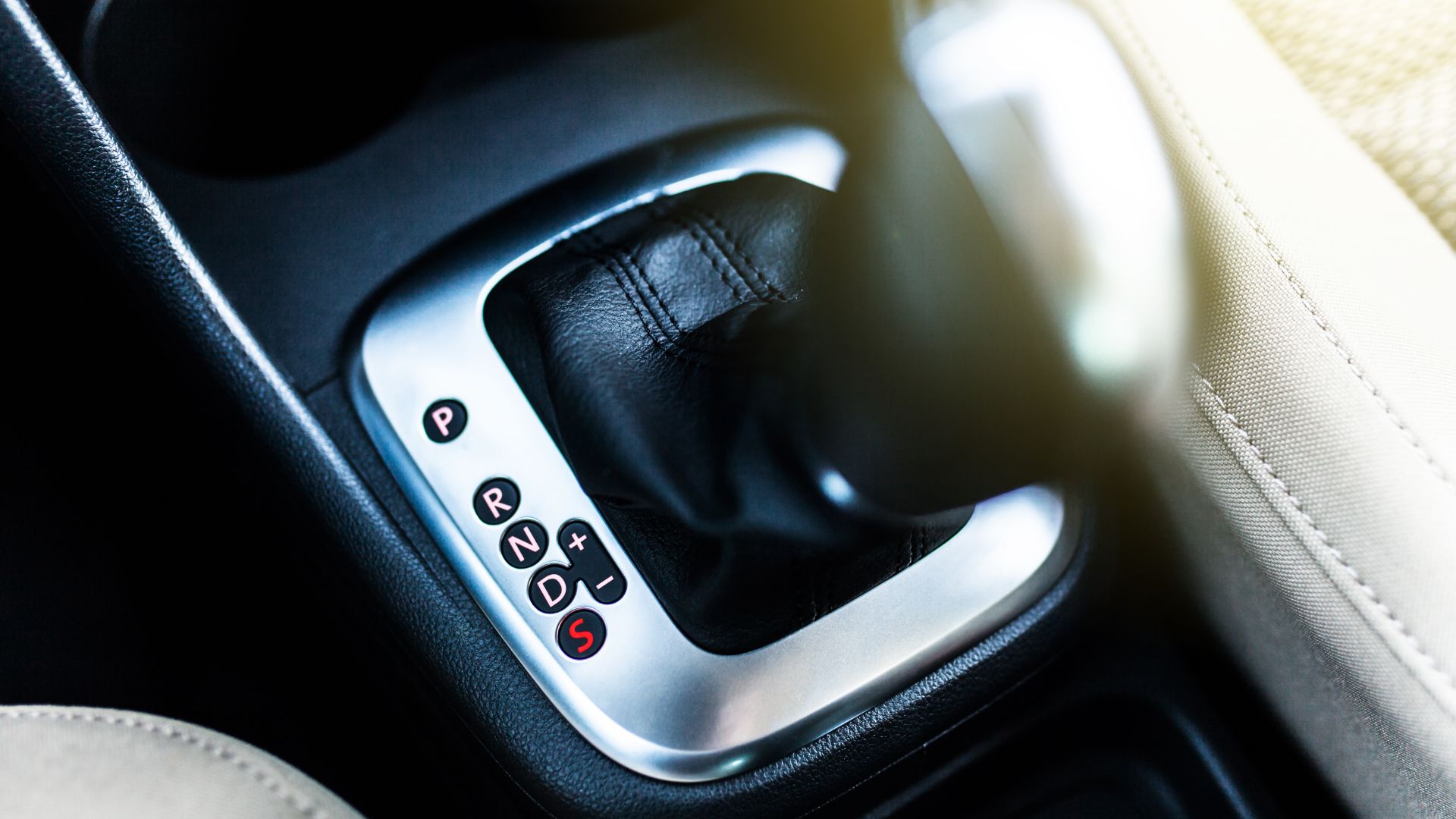 a close up of a button in a car.|a close up of a gear stick in a car.|a close up of a button on a car.|a couple of cars driving down a road next to a forest.