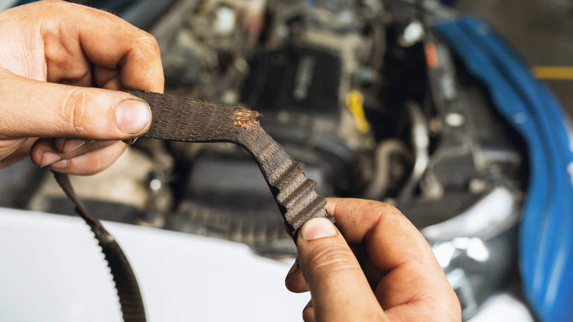 a man holding a wrench in front of a car engine.|a close up of a vehicle's front suspension.