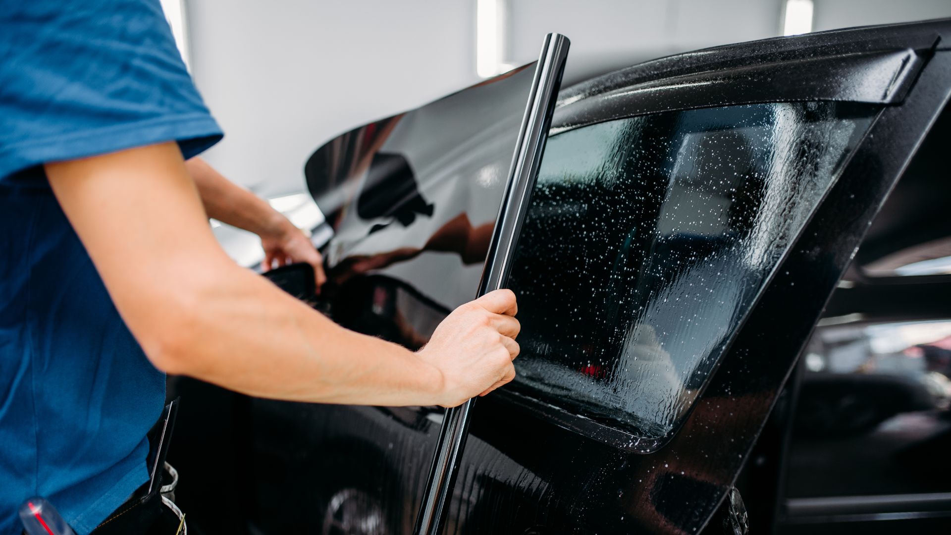 a man waxing a car in a garage.|two hands reaching out of a car window.