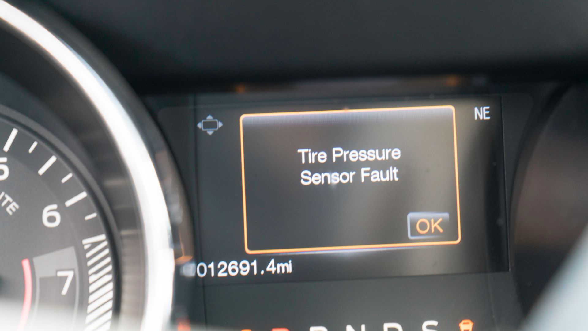 a close up of a gauge on a car.|a black and yellow logo with the words check tire pressure.|a close up of a person standing next to a car tire.