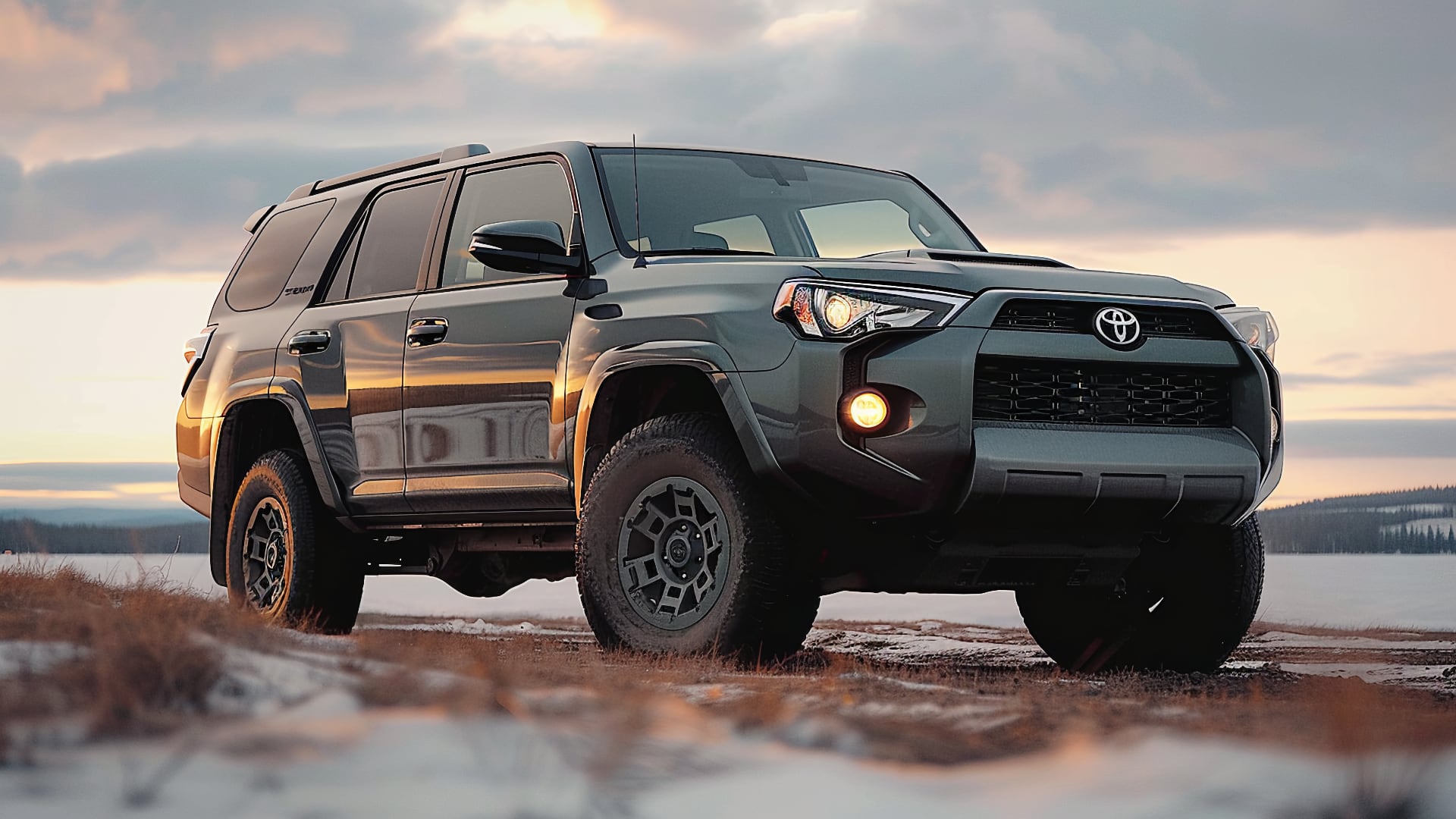 The 2019 Toyota 4Runner is parked on a snowy road.|a black truck is driving down a dirt road.