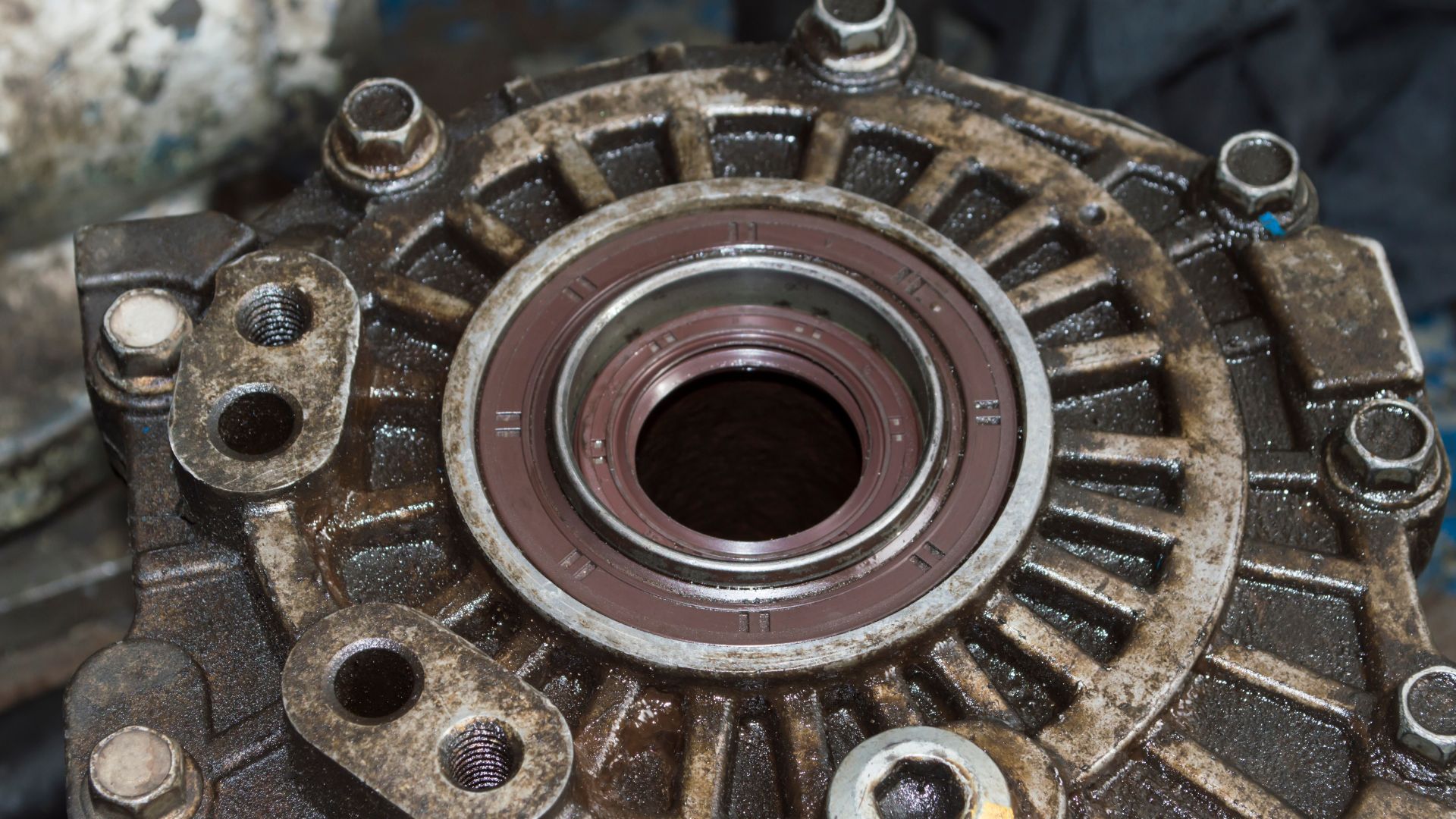 a close up of a metal object with a red background.|a close up of a vehicle under a vehicle.|a dirty engine sitting next to a blue wall.|a close up of an engine on a white background.