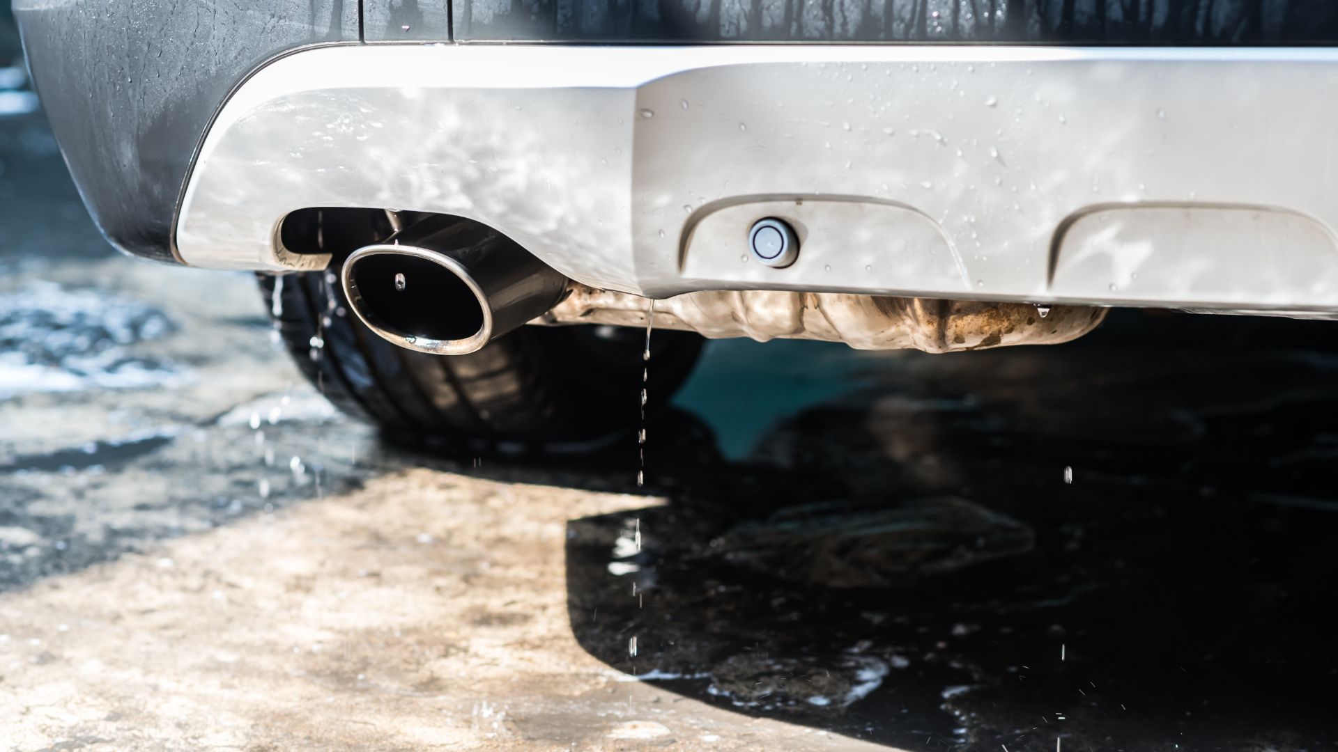 a close up of a car's exhaust system.|a close up of a person working on an engine.