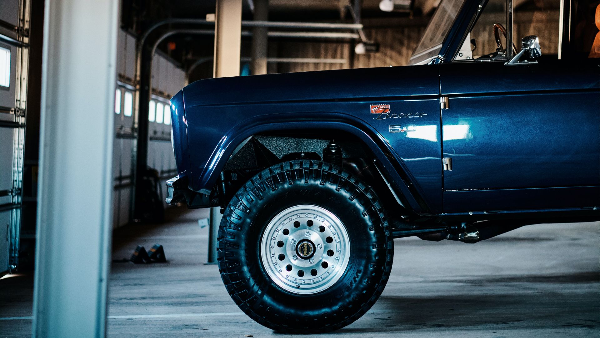 a blue truck parked inside of a garage.|a pile of tires sitting next to each other.