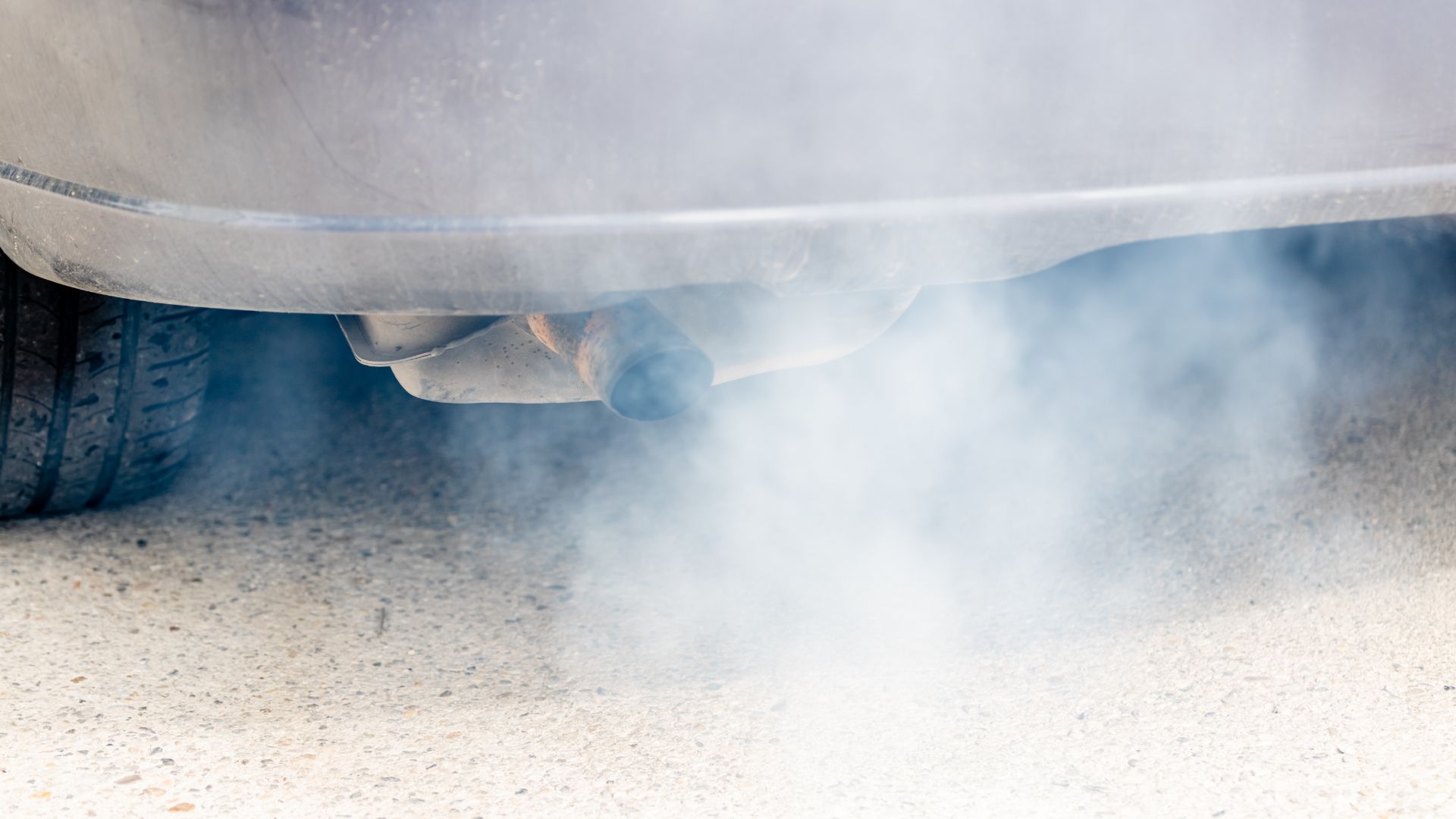 a close up of a car with smoke coming out of it.|a car driving down a snow covered road.